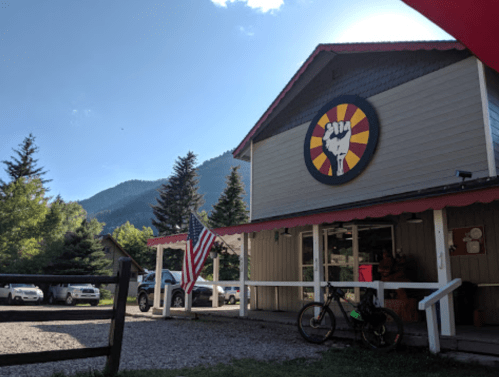 A mountain view with a building featuring a raised fist logo and an American flag in front.