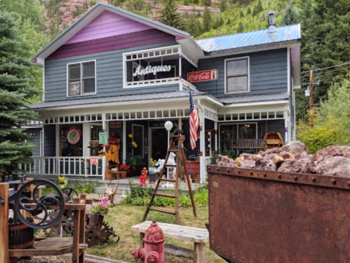 A charming antique shop with a purple and blue exterior, featuring vintage items and a Coca-Cola sign.