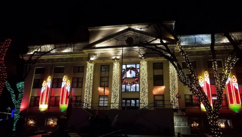 A beautifully lit building at night, adorned with festive decorations, including candles and a wreath.