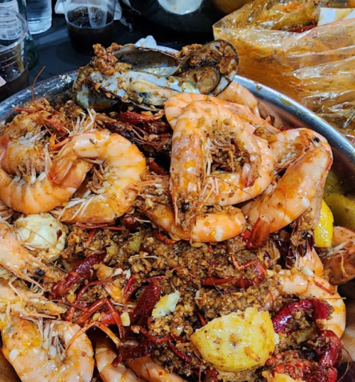 A large platter of shrimp and crawfish mixed with spices and garnishes, showcasing a vibrant seafood feast.