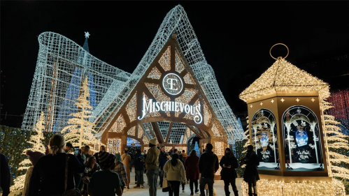 A festive entrance adorned with lights, featuring the word "Mischievous" and a decorative lantern, with people walking in.