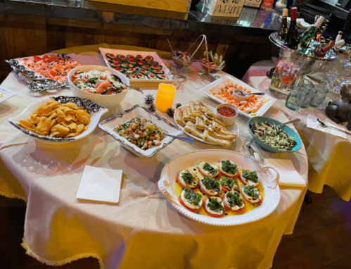A table spread with various appetizers, including chips, salads, seafood, and decorative drinks.