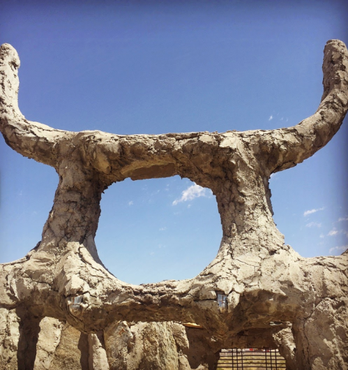A weathered stone structure with a large opening, set against a clear blue sky.