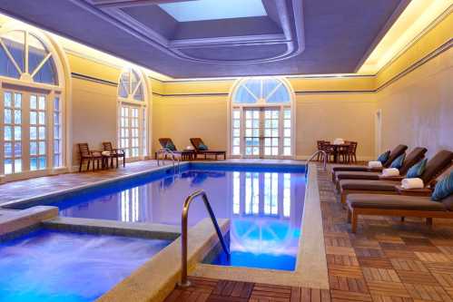 Indoor spa area featuring a pool, lounge chairs, and large windows with natural light. Relaxing atmosphere.