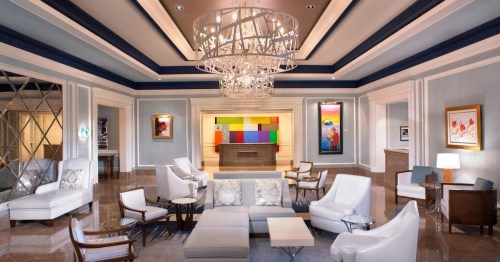Elegant hotel lobby featuring modern furniture, a large chandelier, and colorful artwork on the walls.