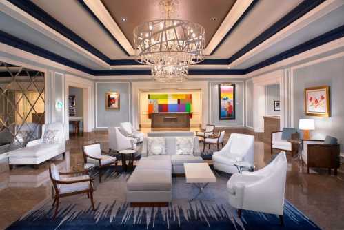 Elegant hotel lobby featuring modern furniture, a large chandelier, and colorful artwork on the walls.