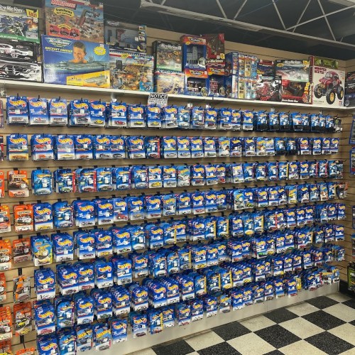A wall display filled with various toy cars and models in packaging, organized neatly on shelves.