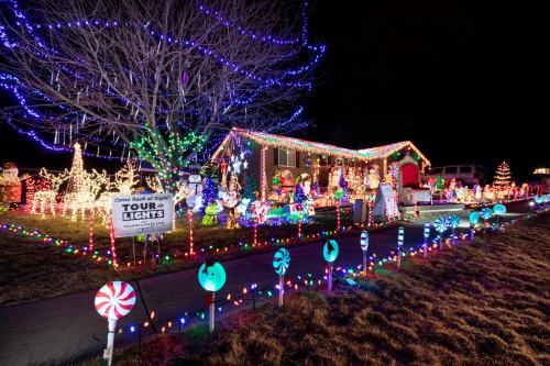 A brightly lit house decorated with colorful Christmas lights, inflatables, and candy-themed decorations at night.