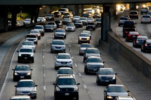 A busy highway with multiple lanes filled with cars during late afternoon traffic.