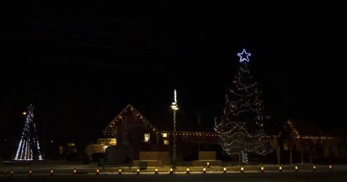 A beautifully lit Christmas tree and decorations illuminate a festive scene at night.