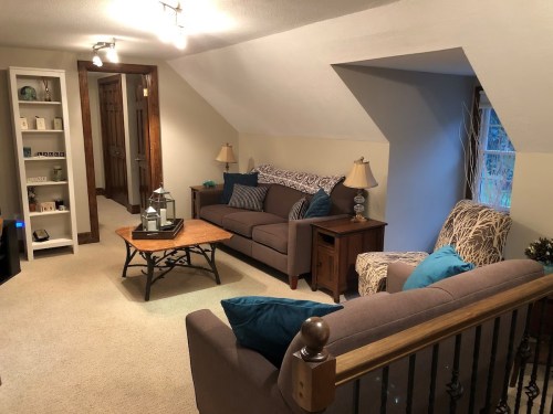 Cozy living room with two sofas, a coffee table, and decorative lamps, featuring a warm, inviting atmosphere.