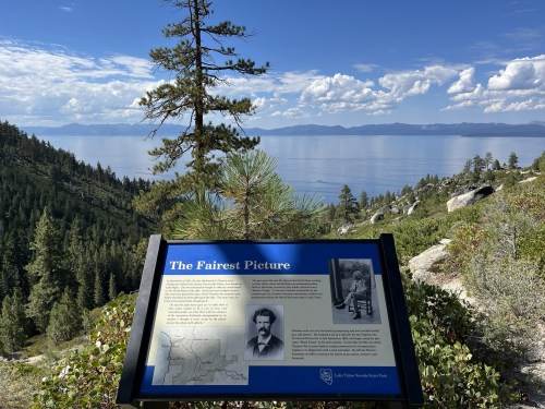 A scenic view of Lake Tahoe with a sign titled "The Fairest Picture" detailing historical information.