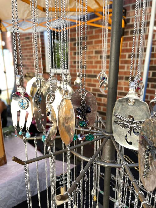A display of silver necklaces hanging on a stand, featuring various pendants and intricate designs.
