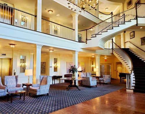 Elegant hotel lobby featuring a grand staircase, plush seating, and decorative lighting.