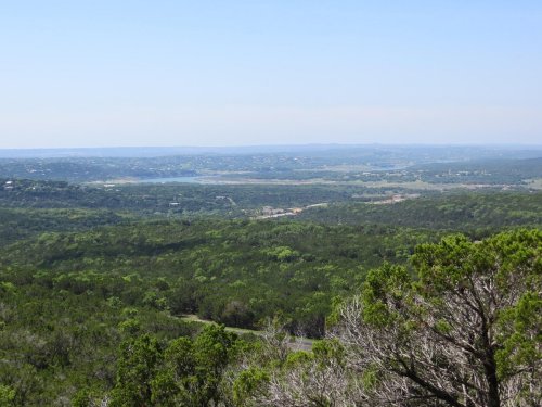 A panoramic view of lush green hills and valleys under a clear blue sky.
