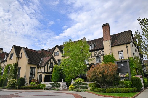 A charming Tudor-style building with lush greenery and a sign for "Shady Inn" under a partly cloudy sky.