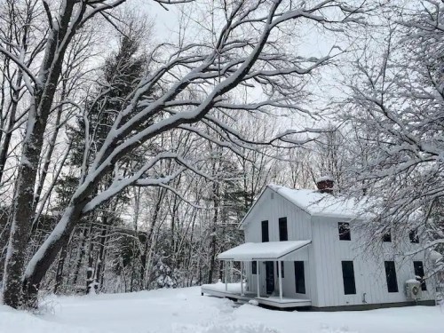 A white house surrounded by snow-covered trees in a winter landscape.