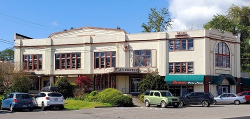 A two-story building with large windows, labeled "Star Center," surrounded by parked cars and greenery.