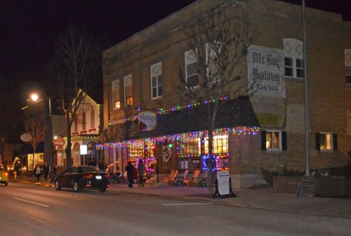 A charming street scene at night, featuring a lit-up building adorned with colorful holiday lights and festive decorations.