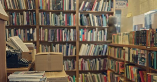 Library interior featuring shelves filled with books, and magazines.