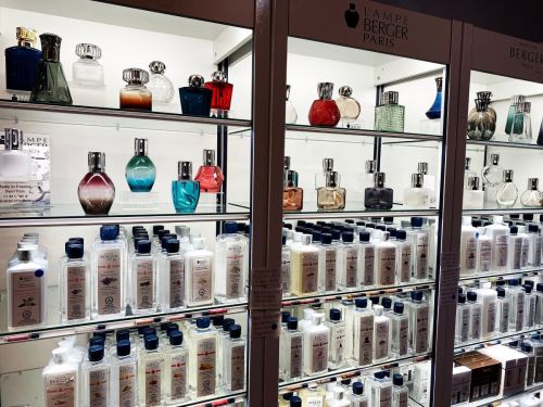 A display of various perfume bottles and home fragrance products on shelves, showcasing different shapes and colors.