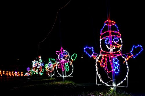 Colorful illuminated snowmen decorations lined up in the dark, creating a festive holiday scene.
