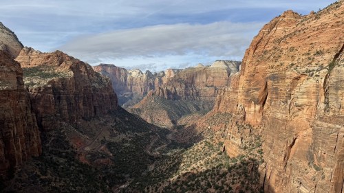 A panoramic view of Zion National Park, showcasing towering red rock cliffs and a winding valley below.