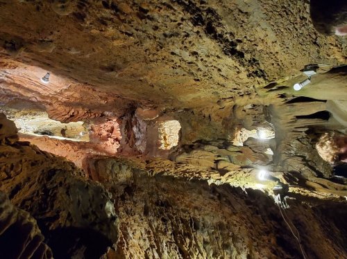 A view of a rocky cave interior with illuminated sections and textured stone walls.