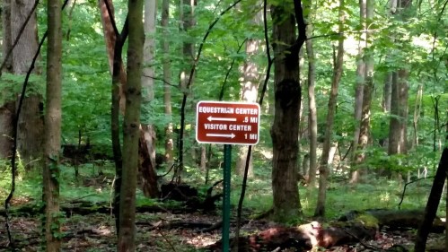 Sign in a forest indicating directions to the Equestrian Center (5 miles) and Visitor Center (1 mile).