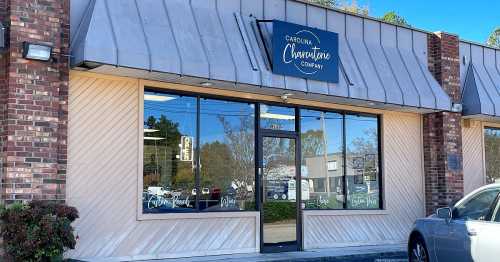 Exterior of the Carolina Charcuterie Company storefront, featuring large windows and a sign above the entrance.