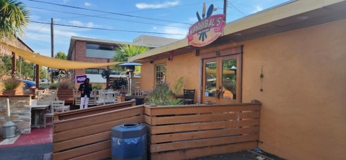 Exterior of a restaurant named "Cannibal's," featuring outdoor seating and a sunny atmosphere.
