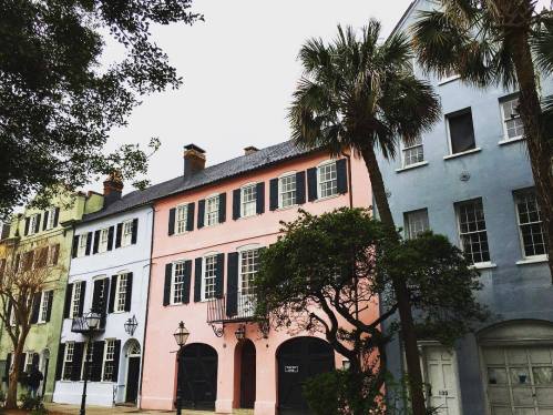 Colorful historic buildings with balconies and palm trees in a charming street scene.