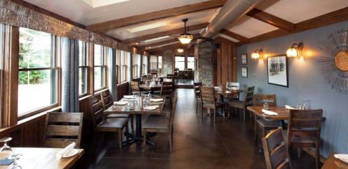 Cozy restaurant interior with wooden tables, chairs, and large windows, featuring a warm, inviting atmosphere.