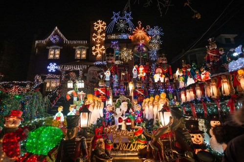 A brightly lit house decorated with colorful Christmas lights, snowmen, nutcrackers, and festive figures.