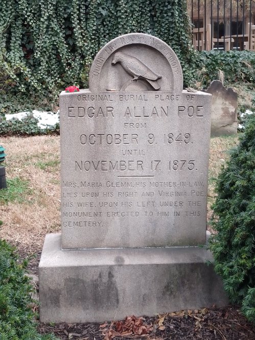 Gravestone of Edgar Allan Poe, detailing his burial dates and family connections, surrounded by greenery.