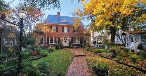 A charming brick bed and breakfast surrounded by colorful autumn foliage and a well-kept garden path.