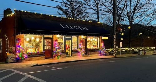 A charming storefront named "Europa" decorated with colorful Christmas lights and trees, set in a cozy evening scene.