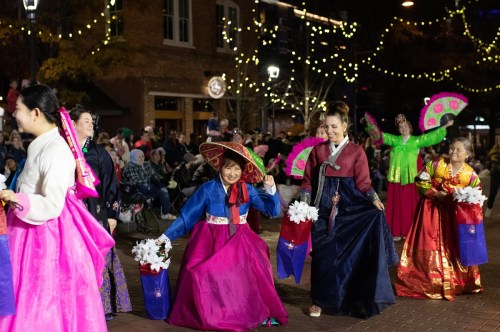 A vibrant cultural festival with dancers in colorful traditional attire, celebrating with flowers and fans.