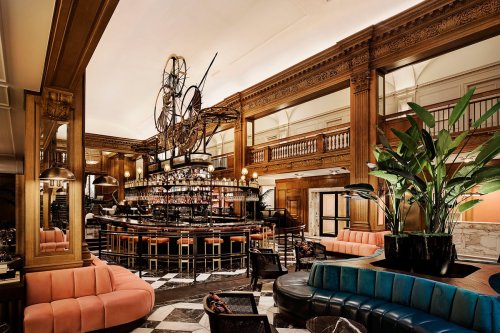 Elegant bar interior featuring a large chandelier, plush seating, and a stylish design with wooden accents.