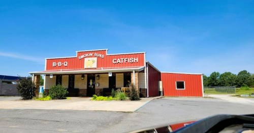A red and beige restaurant building with a sign reading "Smokin Buns BBQ Catfish" under a clear blue sky.