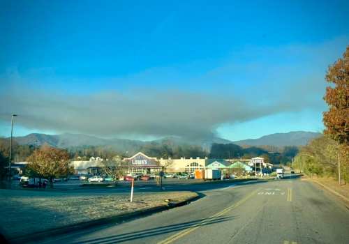 A view of a road leading to a shopping area with mountains in the background, partially obscured by clouds.