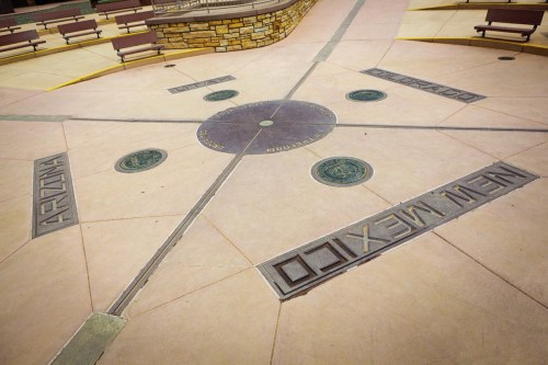 A circular compass design on the ground, featuring state names: Arizona, Colorado, and New Mexico.