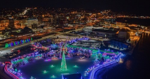 Aerial view of a festive park at night, illuminated with colorful Christmas lights and decorations.