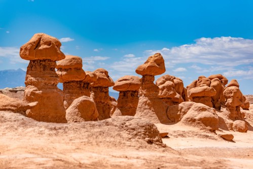 A landscape featuring unique rock formations resembling mushrooms under a clear blue sky.