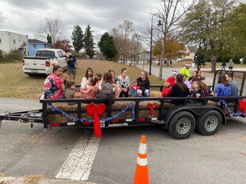 A group of teens sitting on a decorated trailer, enjoying a community event on a cloudy day.