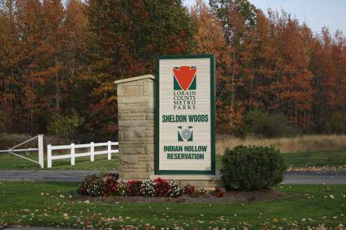 Sign for Lorain County Metro Parks, featuring Sheldon Woods and Indian Hollow Reservation, surrounded by autumn foliage.