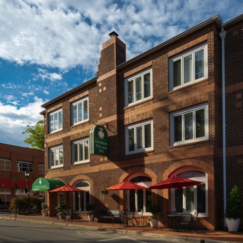 A brick building with large windows and outdoor seating under red umbrellas, featuring a sign for Davidson Village.