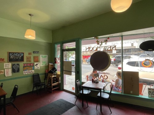 Cozy café interior with green walls, a table by the window, and a view of the street outside.