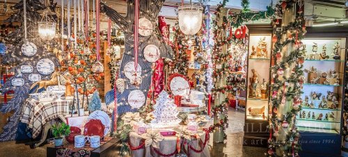 A festive display of holiday decorations, including ornaments, tableware, and themed decor in a warmly lit shop.