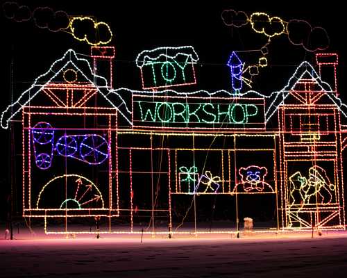 Colorful holiday lights depict a toy workshop with gifts, toys, and festive decorations against a dark background.